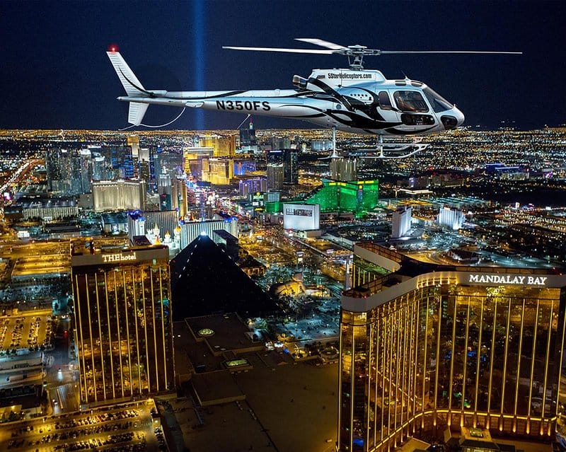 Helicopter over Las Vegas cityscape at night.