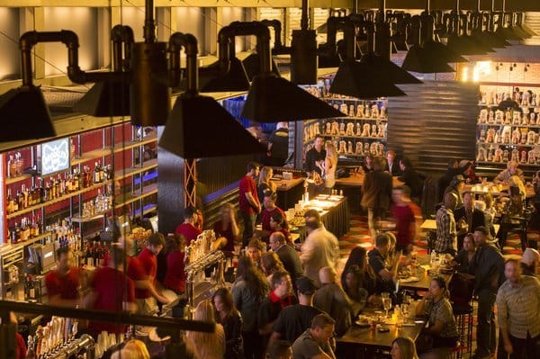 Busy restaurant interior with dark lighting and hanging fixtures.