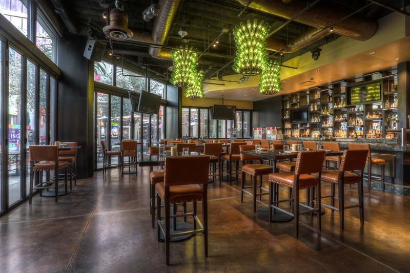 Interior of a modern restaurant with bar seating and green chandeliers.