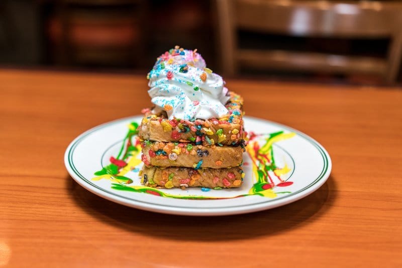 Stack of sprinkle-covered French toast with whipped cream.