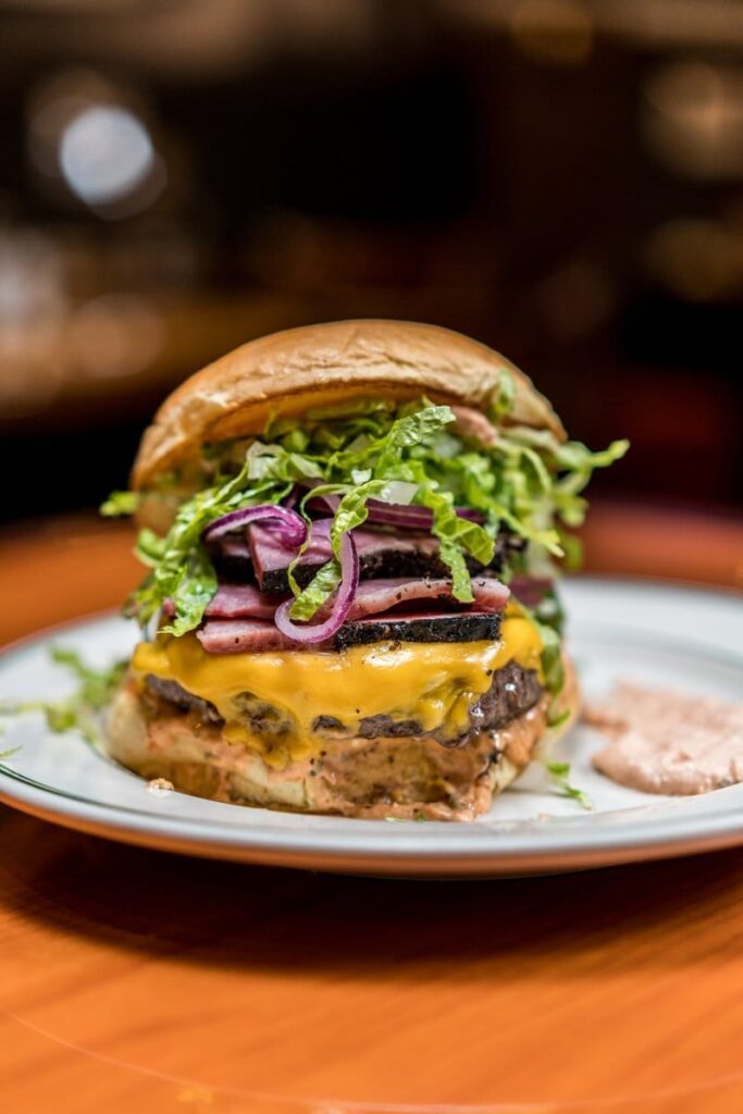 Delicious burger with melted cheese, greens, and sauce.