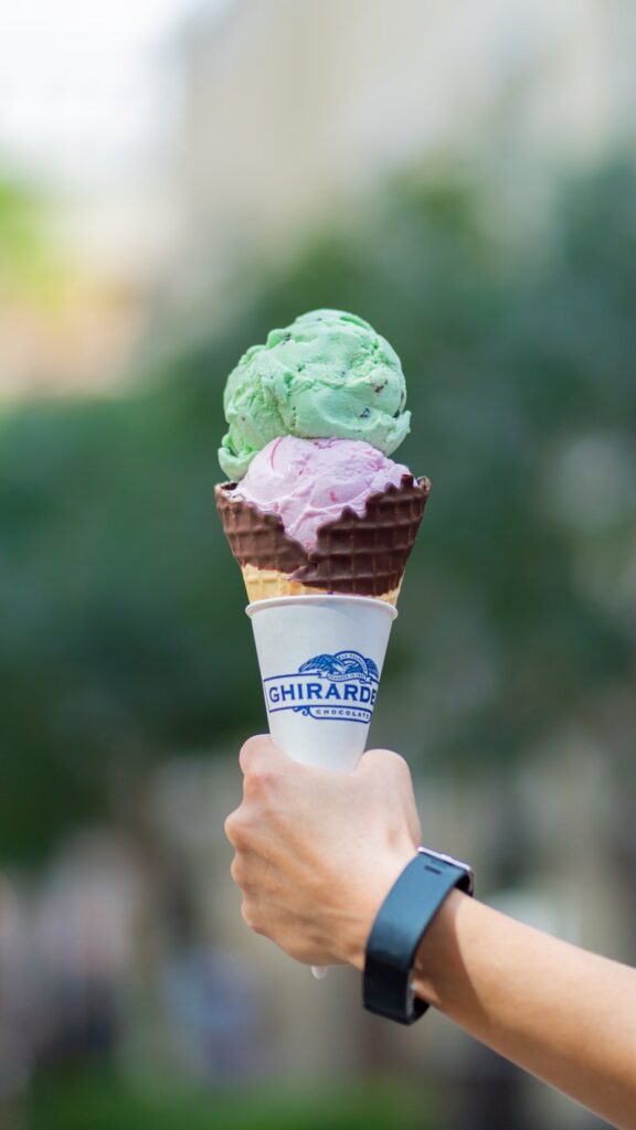 Hand holding a double scoop ice cream cone.