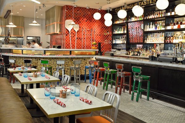 Restaurant interior with bar, tables, and colorful stools.
