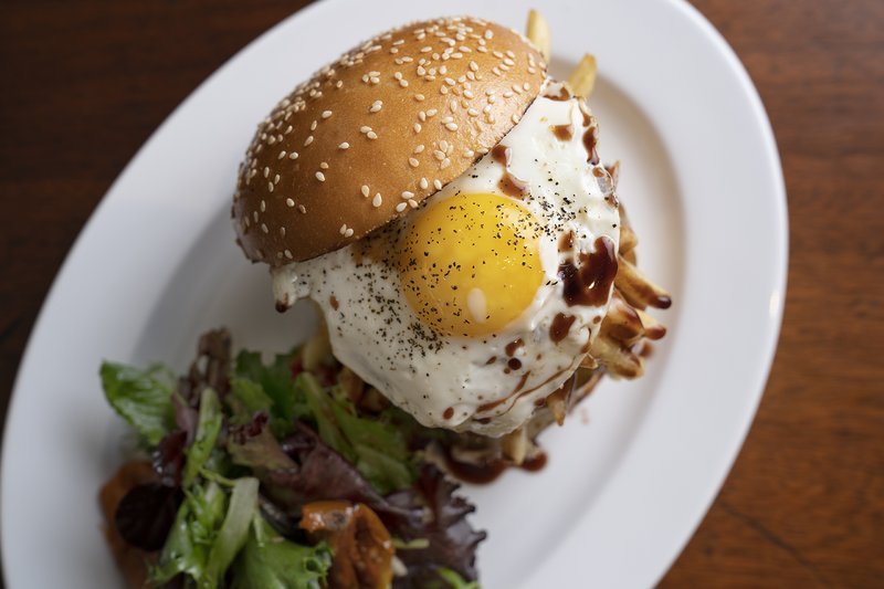 Burger topped with fried egg and salad.