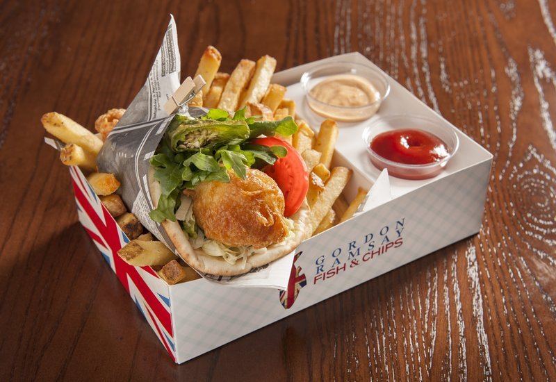 Fish and chips wrap with sauce in takeout container.