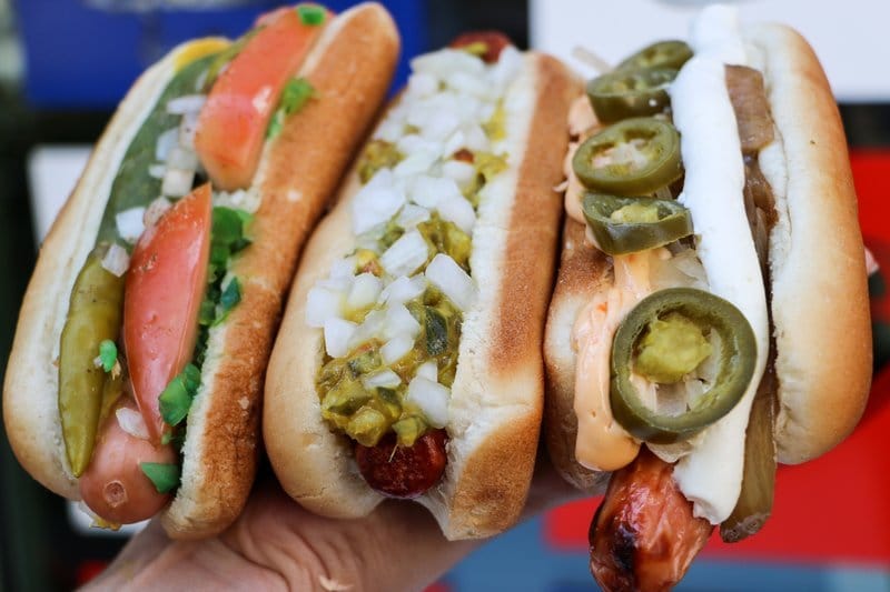 Three gourmet hot dogs with varied toppings.