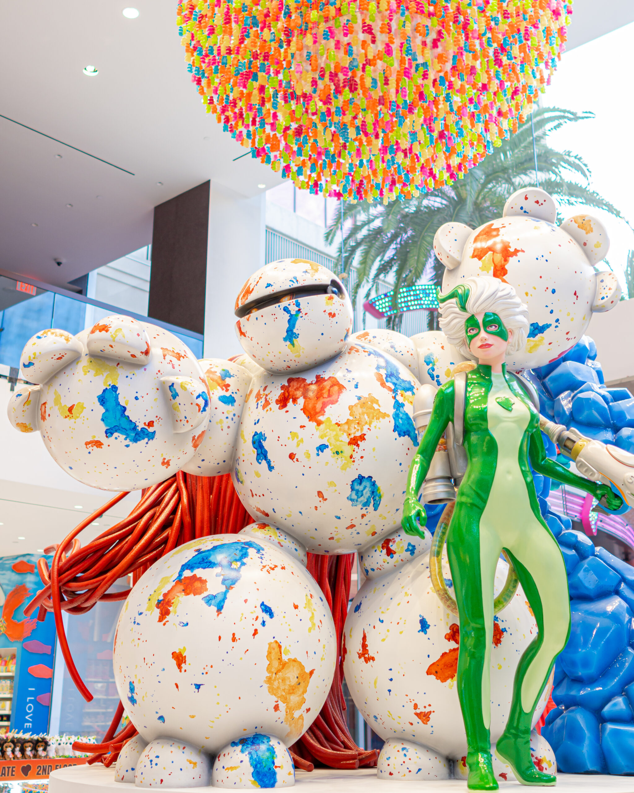 Colorful art installation with superhero figure and teddy bear robot.