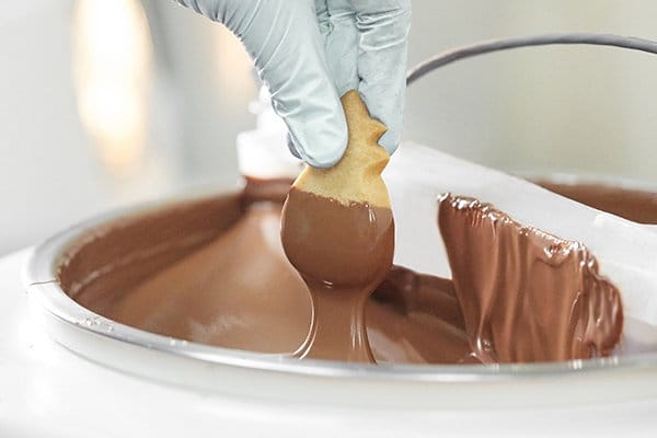 Cookie being dipped in chocolate.