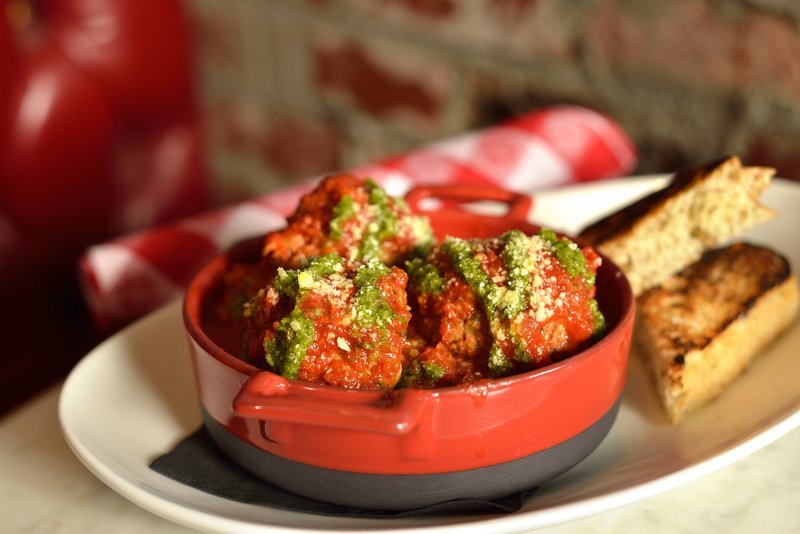 Meatballs in tomato sauce with pesto in red bowl.