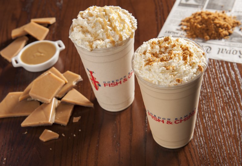 Two milkshakes with whipped cream and toppings.