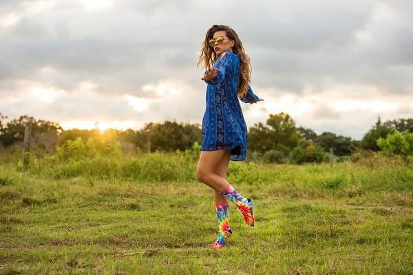 Woman in blue dress and colorful socks dancing in a field.