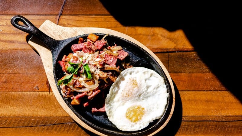 Corned beef hash and fried eggs on a skillet.