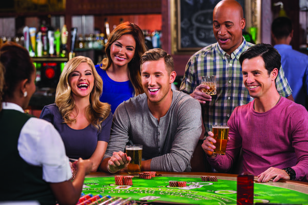 Friends laughing and drinking at a casino craps table.