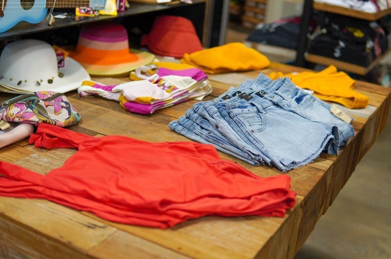 Assorted colorful clothes and hats on a wooden table.