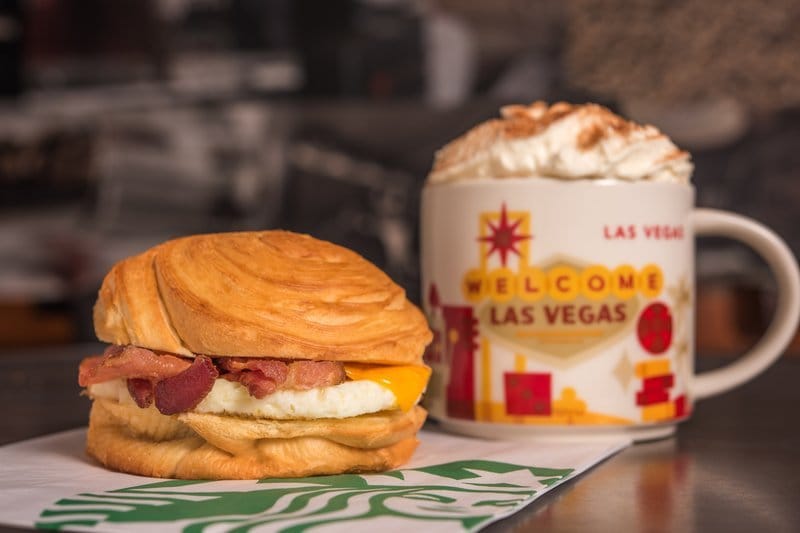 Breakfast croissant sandwich and Las Vegas themed coffee cup.