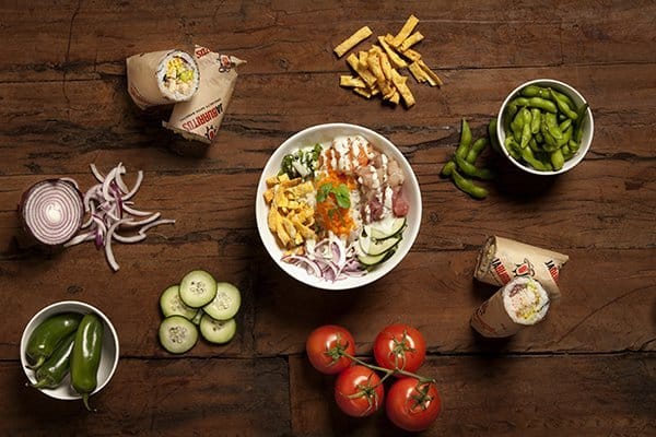 Overhead view of poke bowl with ingredients and sides.