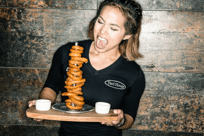 Enthusiastic server presenting tall spiral fries.